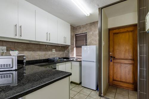 a kitchen with white cabinets and a white refrigerator at Mzingazi Waterfront Accommodation, On The Bay Waterfront Villa's in Richards Bay