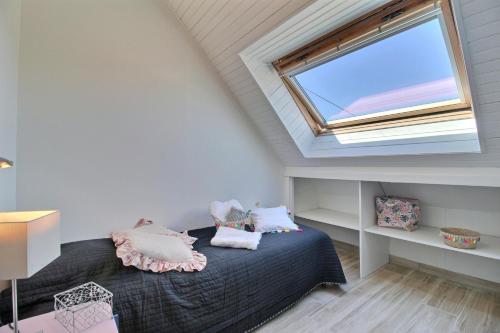 a attic bedroom with a bed with a window at GITE ARC EN CIEL BLEU in Férel