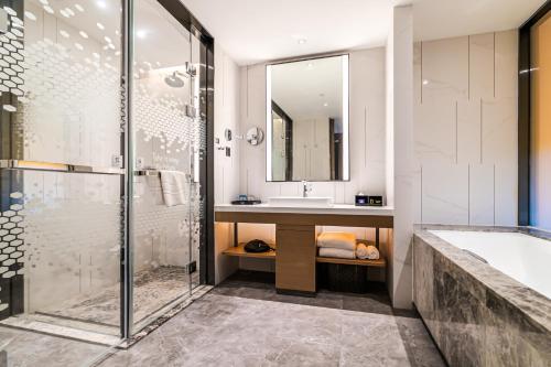 La salle de bains est pourvue d'une douche, d'un lavabo et d'une baignoire. dans l'établissement 敏卓酒店Mentor Hotel, à Foshan