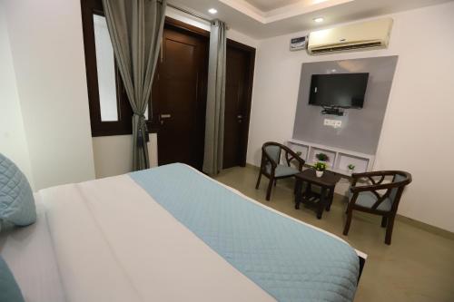 a bedroom with a bed and a table and a tv at Hotel Nature View Green Park Metro Couple Friendly New Delhi in New Delhi