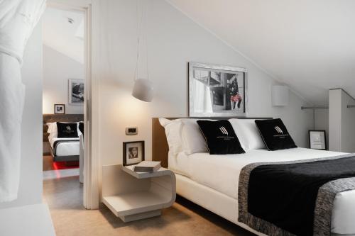 a bedroom with a white bed with black pillows at Montenapoleone Suites in Milan
