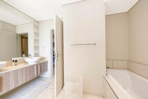 uma casa de banho com uma banheira e 2 lavatórios e uma banheira em Tyrwhitt Luxury Apartment in Rosebank - with generator em Joanesburgo