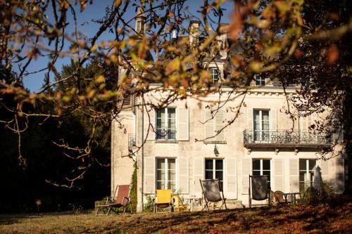 a large white house with chairs in front of it at Château de Charnizay in Charnizay