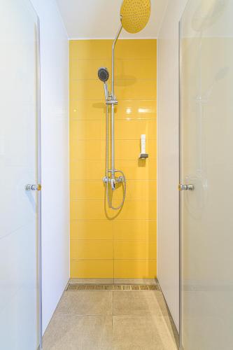 a shower with a yellow wall in a bathroom at Jam Panzió in Kapuvár