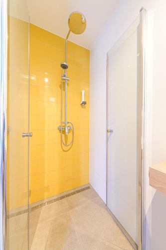 a bathroom with a shower with a yellow wall at Jam Panzió in Kapuvár