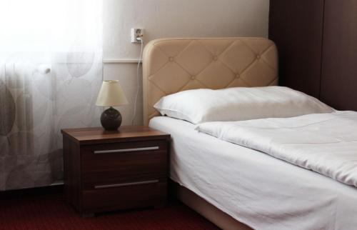 a bedroom with two beds and a night stand with a lamp at Hotel Ďumbier in Brezno