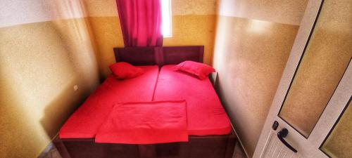 a small room with a red bed with a window at Pam de Terra 