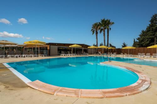 - une grande piscine avec des chaises et des parasols dans un complexe dans l'établissement Camping maeva Escapades Les Cottages de Perpignan, à Perpignan
