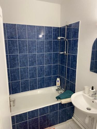 baño de azulejos azules con bañera y lavamanos en Bel appartement spacieux, lumineux avec parking en Ris-Orangis