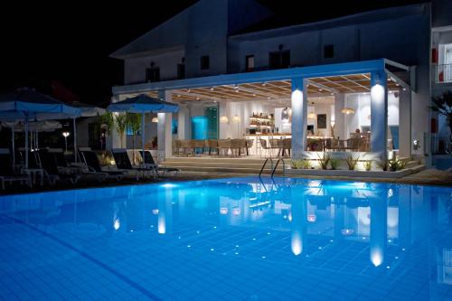 a swimming pool at night with a restaurant at Alfa Hotel in Parga