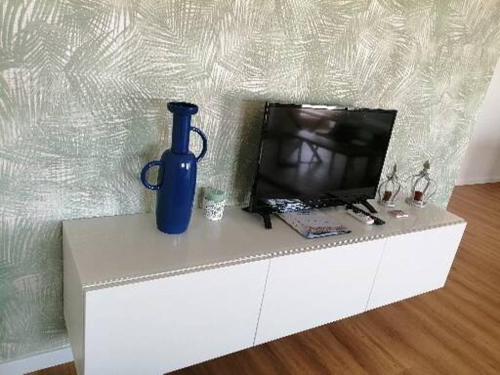 um vaso azul sentado num armário branco com uma televisão em zélu apartamento centro da Guarda na Guarda