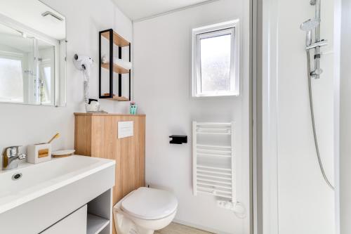 a white bathroom with a toilet and a sink at Camping maeva Escapades Les Cottages de Perpignan in Perpignan