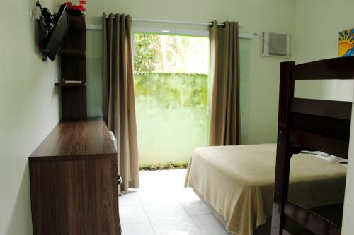 1 dormitorio con 1 cama y puerta corredera de cristal en Sun Suítes en Ubatuba