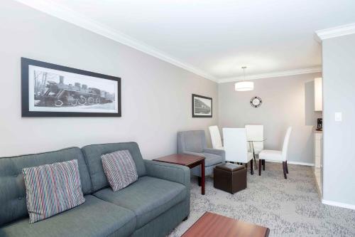 a living room with a couch and a dining room at Sandman Hotel & Suites Prince George in Prince George