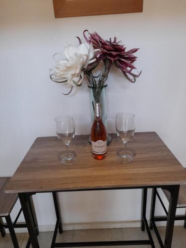 a table with two wine glasses and a vase with flowers at Hospedaje Benacazon A49 in Benacazón