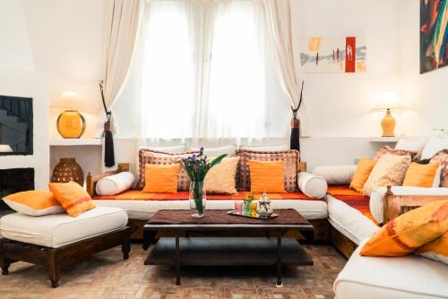 a living room with white couches and orange pillows at Dar Liouba Hotel in Essaouira