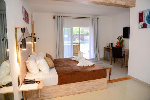 a bedroom with a large bed with a desk and a window at Maison Du Nord in Pointe aux Canonniers