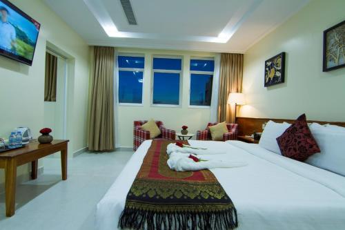 una habitación de hotel con una cama grande y una mesa en Rose Emerald Hotel en Phnom Penh