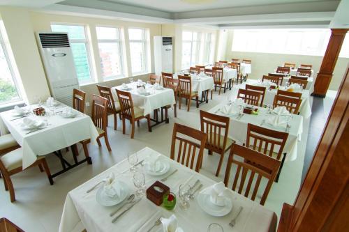 a restaurant with white tables and chairs and windows at Rose Emerald Hotel in Phnom Penh