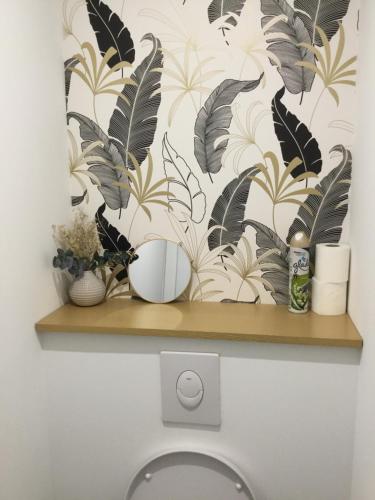 - une étagère au-dessus des toilettes avec du papier peint tropical dans l'établissement Appartement résidence Le Goulvars-plage du Goviro, à Quiberon