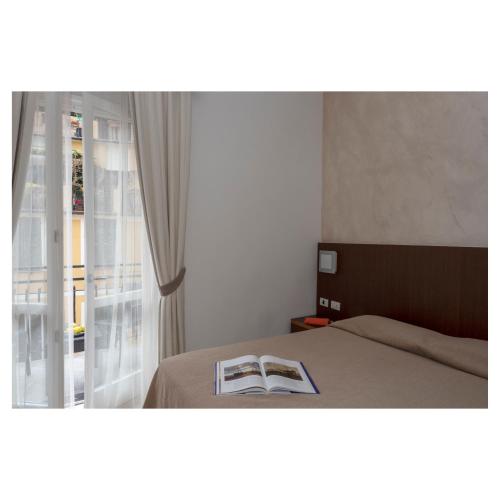a bedroom with a bed and a window with a book at Hotel Margherita in Monterosso al Mare