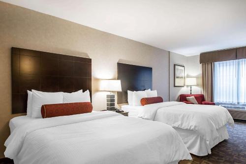 2 camas en una habitación de hotel con sábanas blancas en Clarion Inn Elmhurst - Oak Brook near I-88 I-290 I-294, en Elmhurst