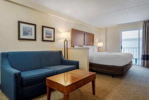 um quarto de hotel com uma cama e um sofá azul em Comfort Inn Ocean City Boardwalk em Ocean City