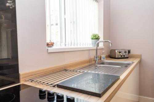 a kitchen counter with a sink and a window at Comfortable 3 Bed House with Parking, WiFi & Patio by Ark SA in Handsworth