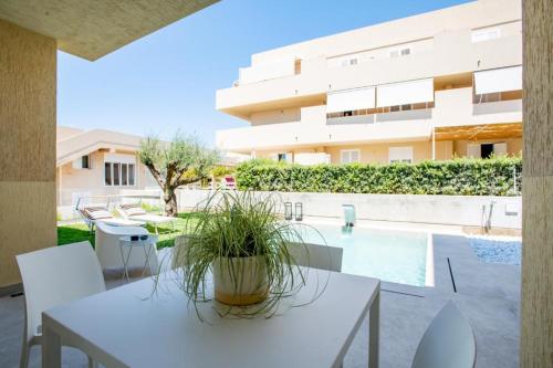 un patio con una mesa y sillas blancas y una piscina en Mediterraneo RELAX HOUSES en Marina di Ragusa