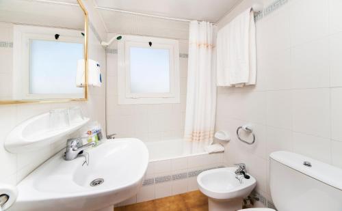 een witte badkamer met een wastafel en een toilet bij Globales Apartamentos Cala Viñas ONLY ADULTS 16 in Cala Vinyes