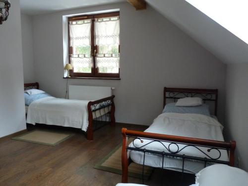 two beds in a room with a window at Kurnik Polski agroturystyka in Tykocin