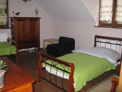 a bedroom with a green bed and a chair at Kurnik Polski agroturystyka in Tykocin