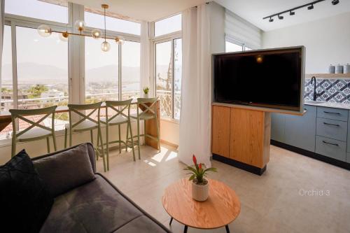 uma sala de estar com uma televisão e uma mesa em YalaRent Orchid Boutique Apartments em Eilat