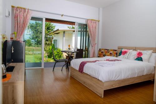 a bedroom with a bed and a large window at Baan Suan Thanwalai Khon Kaen in Khon Kaen