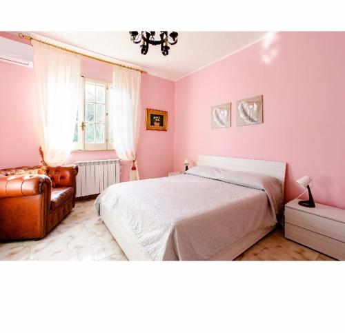 アウグスタにあるVilla Angelaのピンクの壁のベッドルーム(ベッド1台、椅子1脚付)