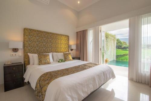 a bedroom with a large bed with a large window at Villa Pondok Maica in Lovina