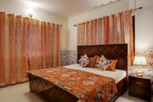 a bedroom with a bed with orange curtains at Meera Homes in Dehradun