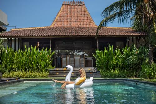 a woman sitting on two swans in a swimming pool at Villa Markisa Echo Beach in Canggu
