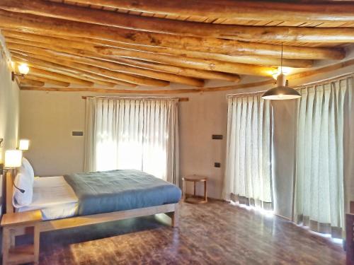 a bedroom with a bed and a wooden ceiling at Dakpa House Ladakh in Ranbirpura