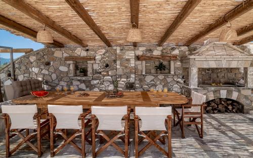 a dining room with a large wooden table and chairs at Akasha Villa, an Alluring Retreat,By ThinkVilla in Zakynthos