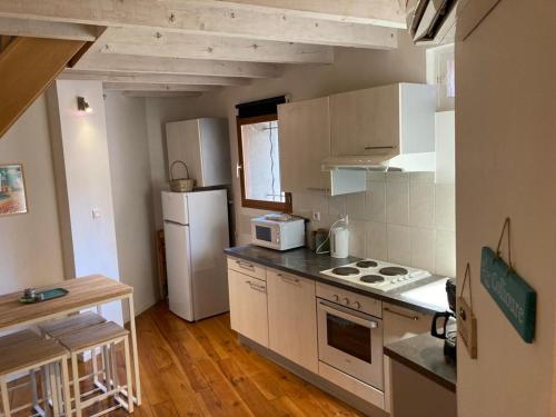 Il comprend une cuisine équipée d'un réfrigérateur blanc et d'une cuisinière. dans l'établissement Appartement de charme centre Collioure, à Collioure