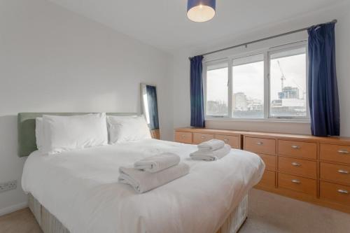 a bedroom with a large white bed with towels on it at A Spacious 2 Bedroom Apartment In Aldgate East in London