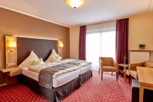 a hotel room with a large bed and a chair at Hotel Sankt Maximilian in Bernkastel-Kues