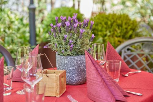 a table with wine glasses and a vase of purple flowers at Hotel Sankt Maximilian in Bernkastel-Kues