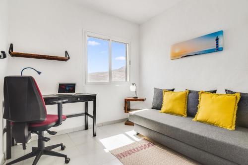 een woonkamer met een bureau, een bank en een computer bij Home2Book Cozy Sea Views Punta Sardina Lighthouse in Gáldar