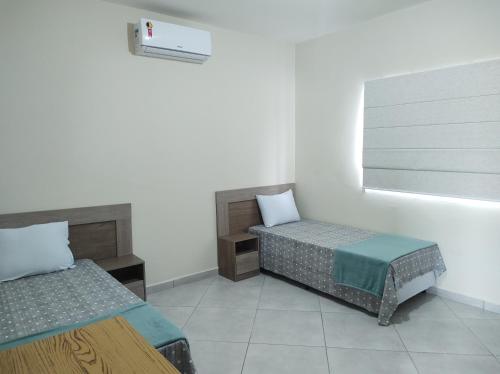 Una habitación con dos camas individuales y una ventana. en Apartamento mobiliado com vista exclusiva da Serra, en Cruzeiro