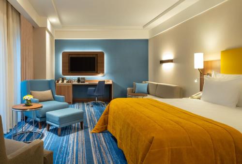 um quarto de hotel com uma cama e uma cadeira e uma televisão em Mövenpick Hotel Istanbul Asia Airport em Istambul