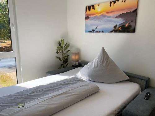 a bedroom with a white bed with a window at Vis Saar Vie - Ferienwohnungen an der Saarschleife in Mettlach