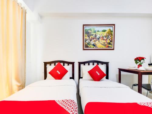 two beds in a room with red and white pillows at OYO 893 Dian Suites Makati in Manila