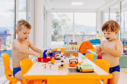 two boys playing with a toy set at a table at Cool Šilo Appartement Resort in Šilo